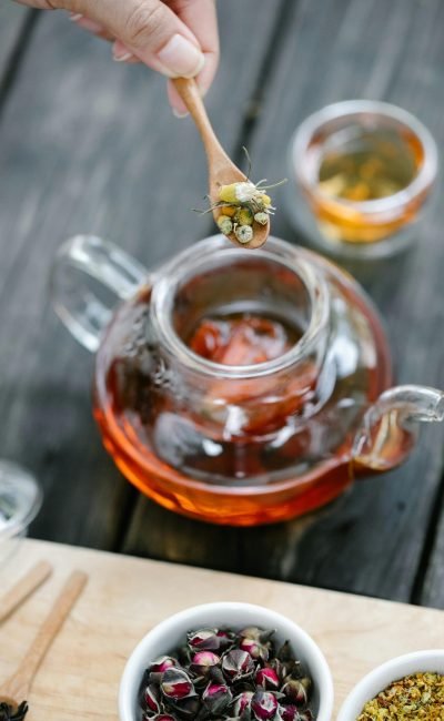 pexels-photo-8329292-8329292 Elevated view of herbal tea preparation using a glass teapot on a rustic wooden table.